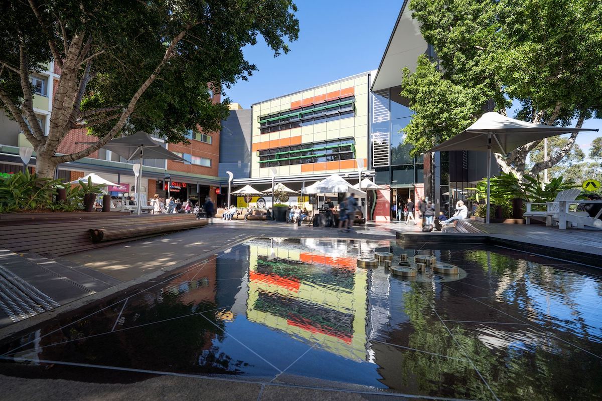 A busy outdoor shopping centre with a water feature